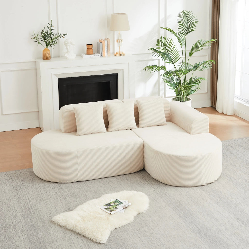 Divano angolare a L in velluto a coste beige con due moduli schienale e braccioli curvi con tre cuscini