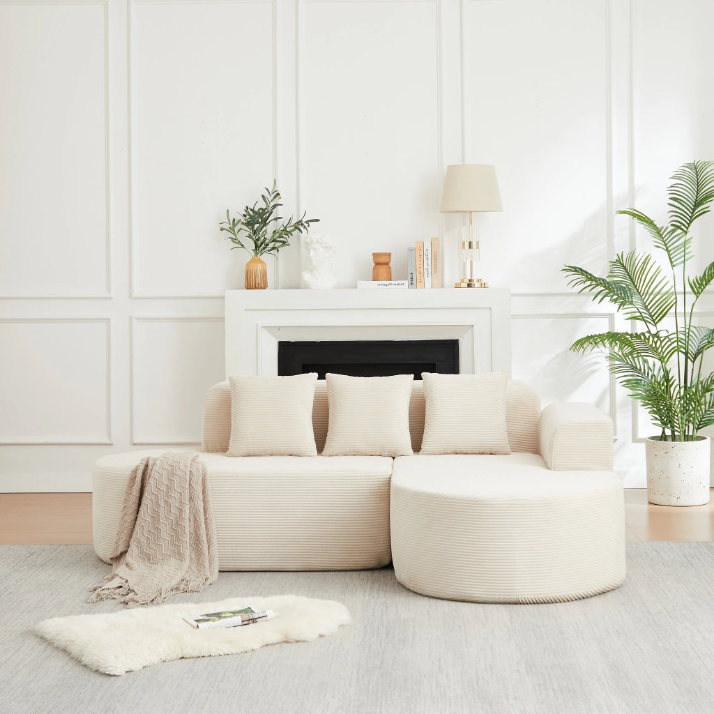 Divano angolare a L in velluto a coste beige con due moduli schienale e braccioli curvi con tre cuscini